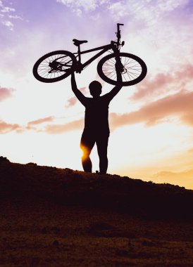 Akşamları yüksek dağlara park etmiş bir dağ bisikletinin silueti pastel bir gökyüzüyle çok güzeldir..