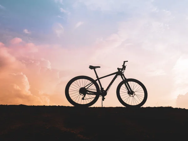 The silhouette of a mountain bike parked high in the mountains in the evening is beautiful with a pastel sky.