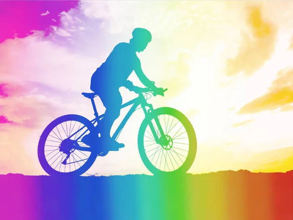 Side view of an active athlete riding a mountain bike on a bike path in the forest in the middle of nature during the colorful sunset. A young man in an exercise suit riding a bicycle on the off-road track.