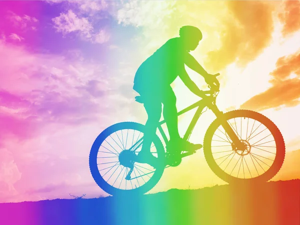 Side view of an active athlete riding a mountain bike on a bike path in the forest in the middle of nature during the colorful sunset. A young man in an exercise suit riding a bicycle on the off-road track.