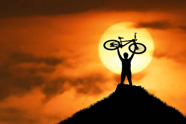 山地自行车手的轮廓使自行车高兴地抬起来 因为他成功了 在傍晚的高山上 它是五彩缤纷的 — 图库照片