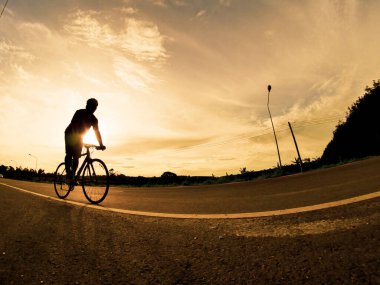 İnsanlar akşamları bisikletle egzersiz yapar. Doğa sporu arka planı. Akşamları arka planda hareket eden bir bisikletçinin görüntüsü