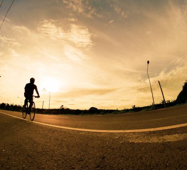 İnsanlar akşamları bisikletle egzersiz yapar. Doğa sporu arka planı. Akşamları arka planda hareket eden bir bisikletçinin görüntüsü