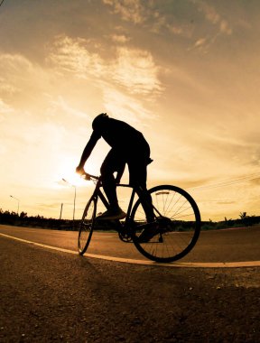 İnsanlar akşamları bisikletle egzersiz yapar. Doğa sporu arka planı. Akşamları arka planda hareket eden bir bisikletçinin görüntüsü