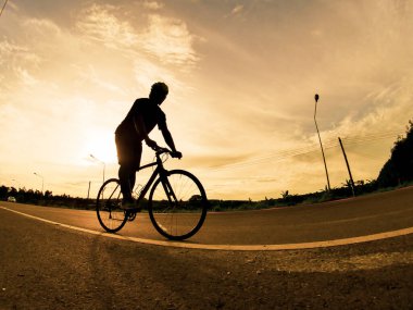 İnsanlar akşamları bisikletle egzersiz yapar. Doğa sporu arka planı. Akşamları arka planda hareket eden bir bisikletçinin görüntüsü