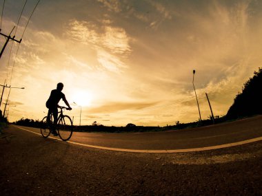 İnsanlar akşamları bisikletle egzersiz yapar. Doğa sporu arka planı. Akşamları arka planda hareket eden bir bisikletçinin görüntüsü