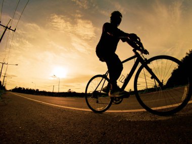 İnsanlar akşamları bisikletle egzersiz yapar. Doğa sporu arka planı. Akşamları arka planda hareket eden bir bisikletçinin görüntüsü