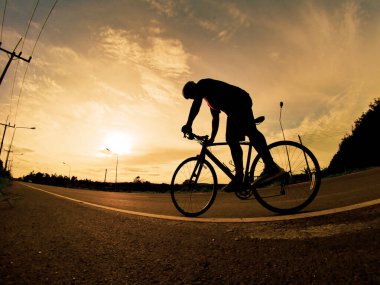 İnsanlar akşamları bisikletle egzersiz yapar. Doğa sporu arka planı. Akşamları arka planda hareket eden bir bisikletçinin görüntüsü