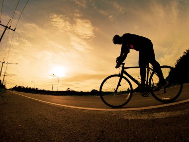 İnsanlar akşamları bisikletle egzersiz yapar. Doğa sporu arka planı. Akşamları arka planda hareket eden bir bisikletçinin görüntüsü