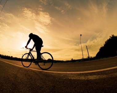 İnsanlar akşamları bisikletle egzersiz yapar. Doğa sporu arka planı. Akşamları arka planda hareket eden bir bisikletçinin görüntüsü