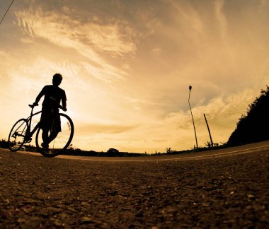 İnsanlar akşamları bisikletle egzersiz yapar. Doğa sporu arka planı. Akşamları arka planda hareket eden bir bisikletçinin görüntüsü