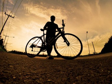 İnsanlar akşamları bisikletle egzersiz yapar. Doğa sporu arka planı. Akşamları arka planda hareket eden bir bisikletçinin görüntüsü
