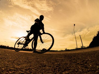 İnsanlar akşamları bisikletle egzersiz yapar. Doğa sporu arka planı. Akşamları arka planda hareket eden bir bisikletçinin görüntüsü