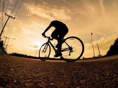 İnsanlar akşamları bisikletle egzersiz yapar. Doğa sporu arka planı. Akşamları arka planda hareket eden bir bisikletçinin görüntüsü