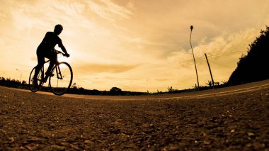 İnsanlar akşamları bisikletle egzersiz yapar. Doğa sporu arka planı. Akşamları arka planda hareket eden bir bisikletçinin görüntüsü