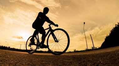 İnsanlar akşamları bisikletle egzersiz yapar. Doğa sporu arka planı. Akşamları arka planda hareket eden bir bisikletçinin görüntüsü