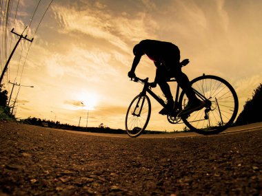 İnsanlar akşamları bisikletle egzersiz yapar. Doğa sporu arka planı. Akşamları arka planda hareket eden bir bisikletçinin görüntüsü