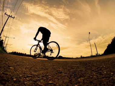 İnsanlar akşamları bisikletle egzersiz yapar. Doğa sporu arka planı. Akşamları arka planda hareket eden bir bisikletçinin görüntüsü