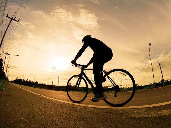 İnsanlar akşamları bisikletle egzersiz yapar. Doğa sporu arka planı. Akşamları arka planda hareket eden bir bisikletçinin görüntüsü