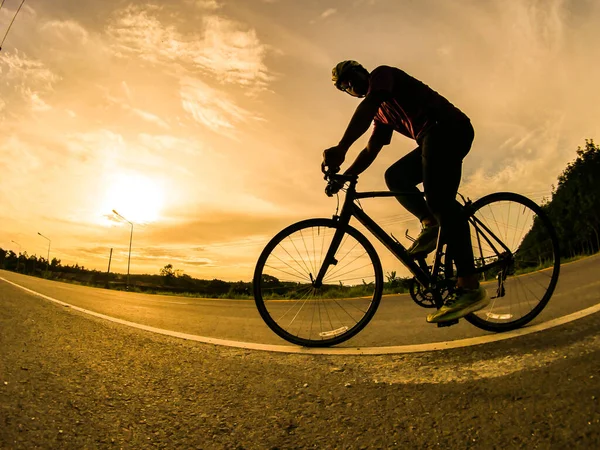 İnsanlar akşamları bisikletle egzersiz yapar. Doğa sporu arka planı. Akşamları arka planda hareket eden bir bisikletçinin görüntüsü