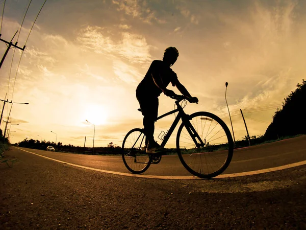İnsanlar akşamları bisikletle egzersiz yapar. Doğa sporu arka planı. Akşamları arka planda hareket eden bir bisikletçinin görüntüsü