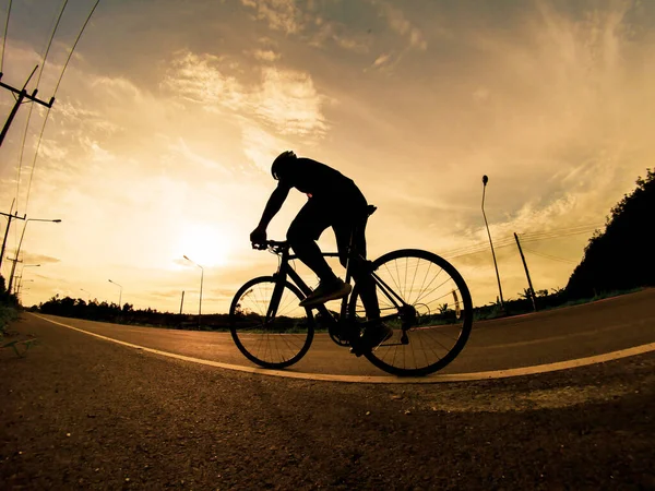 İnsanlar akşamları bisikletle egzersiz yapar. Doğa sporu arka planı. Akşamları arka planda hareket eden bir bisikletçinin görüntüsü