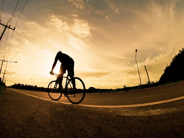İnsanlar akşamları bisikletle egzersiz yapar. Doğa sporu arka planı. Akşamları arka planda hareket eden bir bisikletçinin görüntüsü