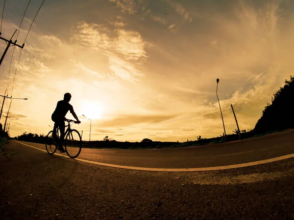 İnsanlar akşamları bisikletle egzersiz yapar. Doğa sporu arka planı. Akşamları arka planda hareket eden bir bisikletçinin görüntüsü