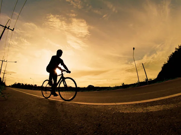 İnsanlar akşamları bisikletle egzersiz yapar. Doğa sporu arka planı. Akşamları arka planda hareket eden bir bisikletçinin görüntüsü