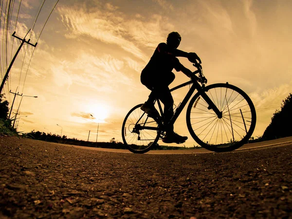 İnsanlar akşamları bisikletle egzersiz yapar. Doğa sporu arka planı. Akşamları arka planda hareket eden bir bisikletçinin görüntüsü