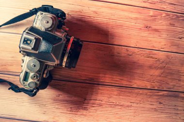 Kahverengi ahşap bir masanın üzerinde içi boş eski bir kamera..