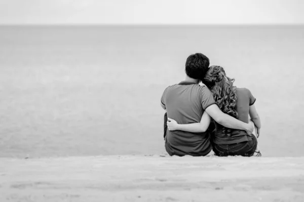 ビーチに座って黒と白のカップルの後ろの景色 — ストック写真