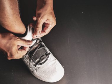 COVID-19 krizinden sonra antrenmana hazırlanmak için ayakkabı askısı bağlayan atletlerin yakın çekimleri.