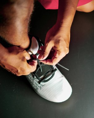 COVID-19 krizinden sonra antrenmana hazırlanmak için ayakkabı askısı bağlayan atletlerin yakın çekimleri.