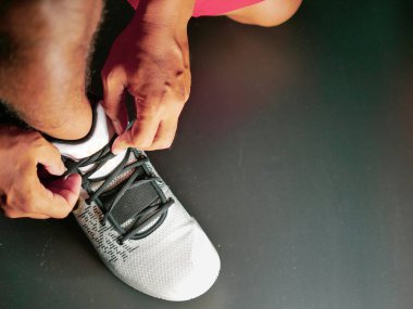 COVID-19 krizinden sonra antrenmana hazırlanmak için ayakkabı askısı bağlayan atletlerin yakın çekimleri.