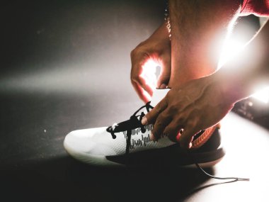 COVID-19 krizinden sonra antrenmana hazırlanmak için ayakkabı askısı bağlayan atletlerin yakın çekimleri.