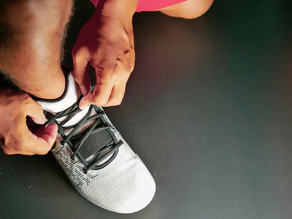 COVID-19 krizinden sonra antrenmana hazırlanmak için ayakkabı askısı bağlayan atletlerin yakın çekimleri.