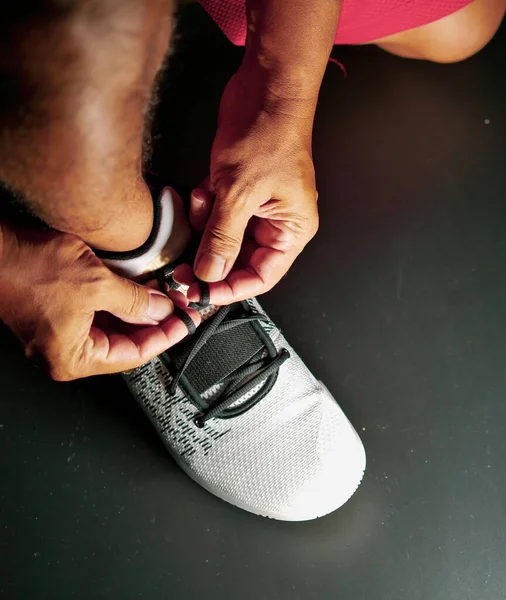 COVID-19 krizinden sonra antrenmana hazırlanmak için ayakkabı askısı bağlayan atletlerin yakın çekimleri.