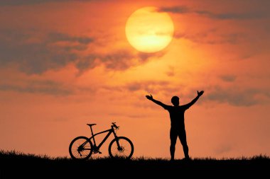 Arka planda günbatımı gökyüzü olan insan ve bisiklet siluetleri