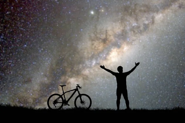 空に星が見える丘の上の男と自転車のシルエット — ストック写真