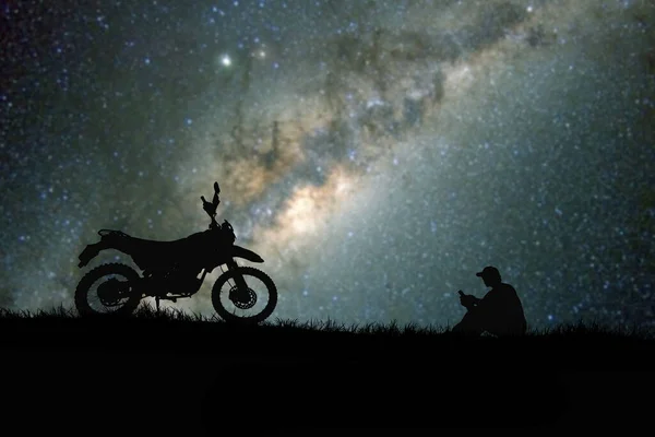 silhouettes of man and bike on hilltop with stars in sky