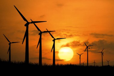 Rüzgar türbininin siluetleri akşam saatlerinde tarlalarda elektrik üretmek için kullanılır..