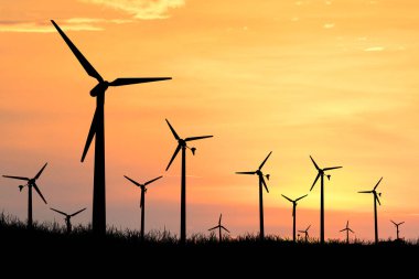 Rüzgar türbininin siluetleri akşam saatlerinde tarlalarda elektrik üretmek için kullanılır..