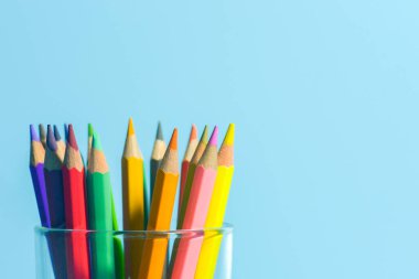 Mavi arkaplanda camlı renkli kalemler, boşluğu kopyala