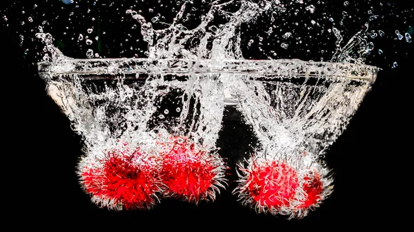 Rambutan Fällt Wasser Auf Schwarzem Hintergrund — Stockfoto
