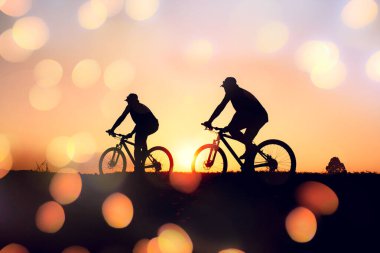 Günbatımının karanlık arka planında bisikletçi ve bisiklet siluetleri dolu