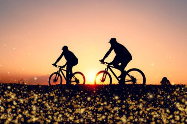 Günbatımının karanlık arka planında bisikletçi ve bisiklet siluetleri dolu