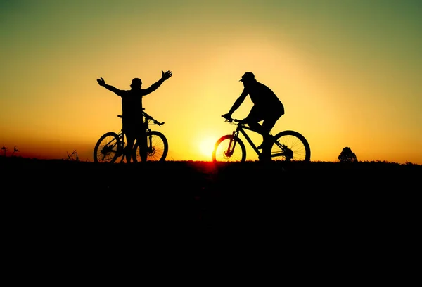 色彩艳丽的骑自行车和骑自行车的人在日落的黑暗背景下的轮廓 — 图库照片