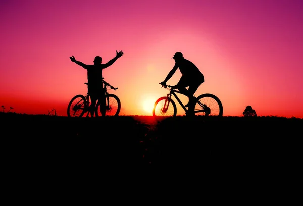 色彩艳丽的骑自行车和骑自行车的人在日落的黑暗背景下的轮廓 — 图库照片