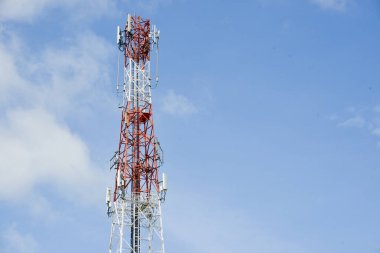 Arka planda büyük bir iletişim kulesi gökyüzü ve bulutlardır..